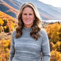 Portrait of Kirsten Alburg smiling outdoors in front of a lake and autumn hillside